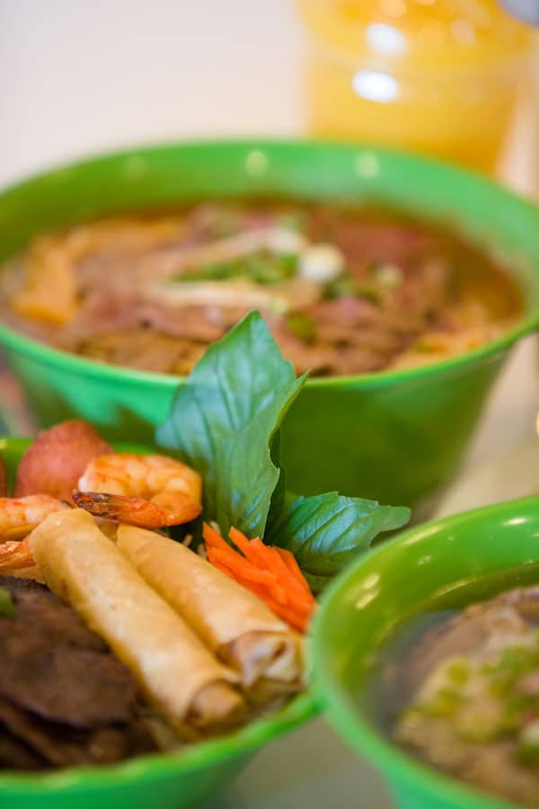 A cook ladling broth from a large stockpot in the Pho Dau Bo kitchen